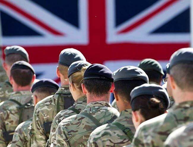 A line of soldiers facing the UK flag