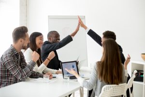 Excited diverse colleagues or partners giving high-five at team