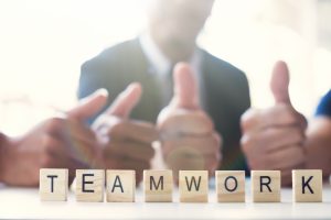 “Teamwork” word on business working table. Wooden cross word alphabet “Teamwork”. Business teamwork concept.