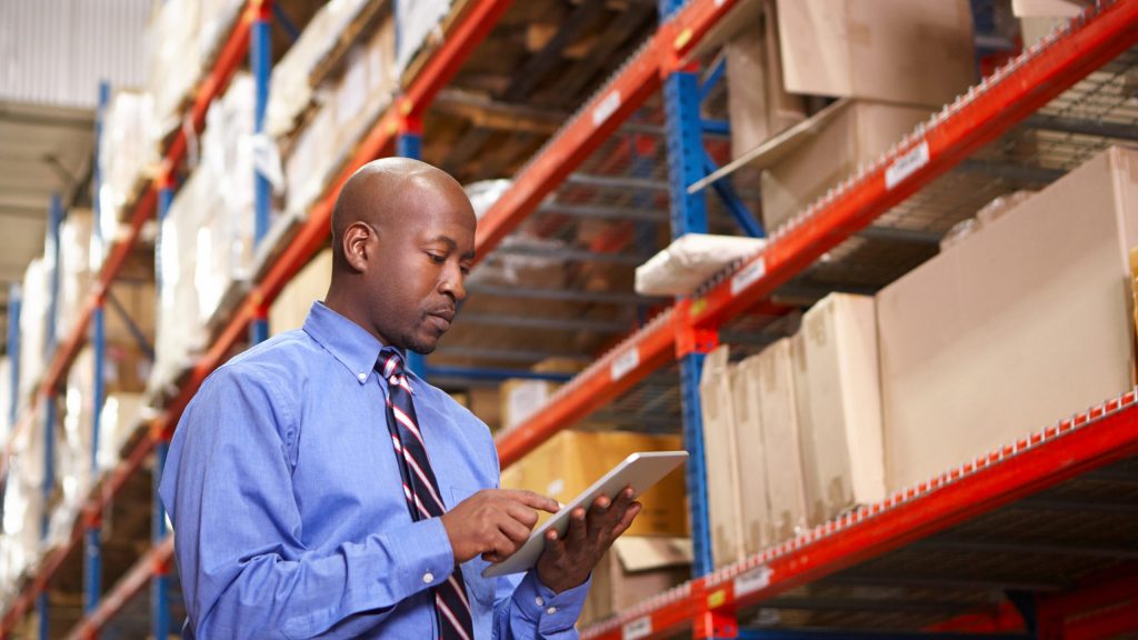 Warehouse manager looking at tablet and reviewing storage procedures